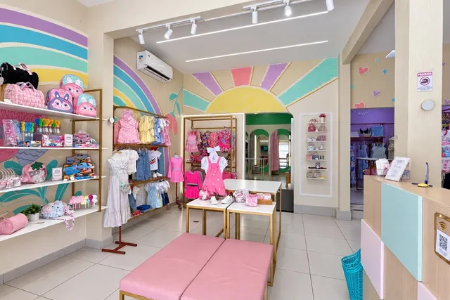 Cantinho da Mini Maricota na loja, com parede de sol e arco-íris, mochilas e roupas infantis