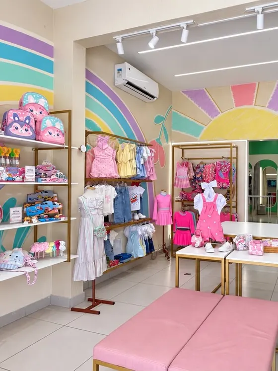 Cantinho da Mini Maricota na loja, com parede de sol e arco-íris, mochilas e roupas infantis